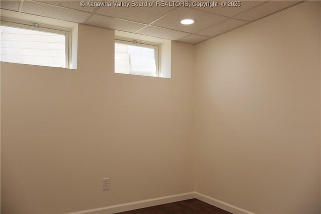 empty room with dark hardwood / wood-style flooring and a paneled ceiling