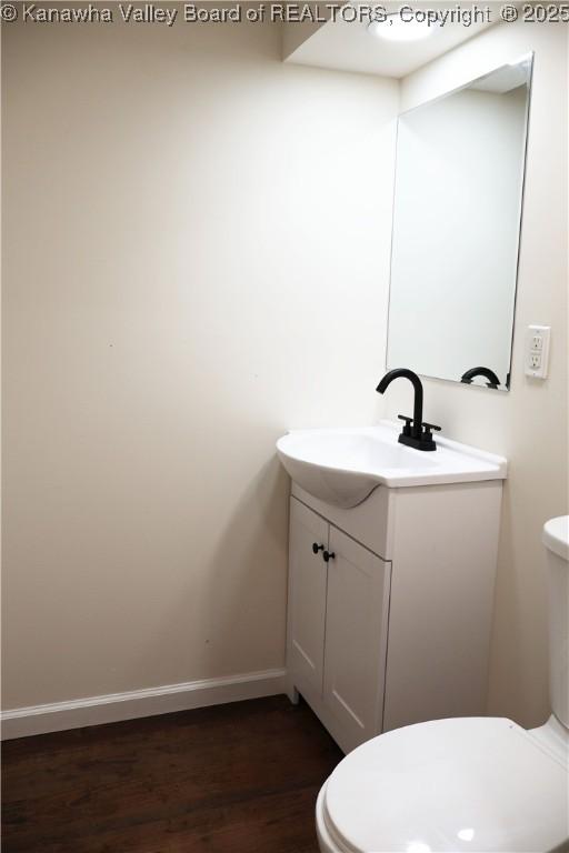 bathroom featuring wood-type flooring, toilet, and vanity