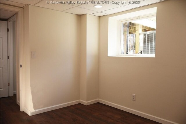 empty room with dark hardwood / wood-style floors and a paneled ceiling