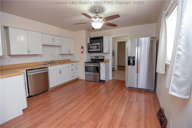 kitchen featuring sink, light wood-type flooring, stainless steel appliances, decorative backsplash, and white cabinets