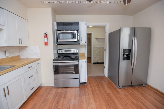 kitchen featuring wood counters, tasteful backsplash, stainless steel appliances, light hardwood / wood-style floors, and white cabinets