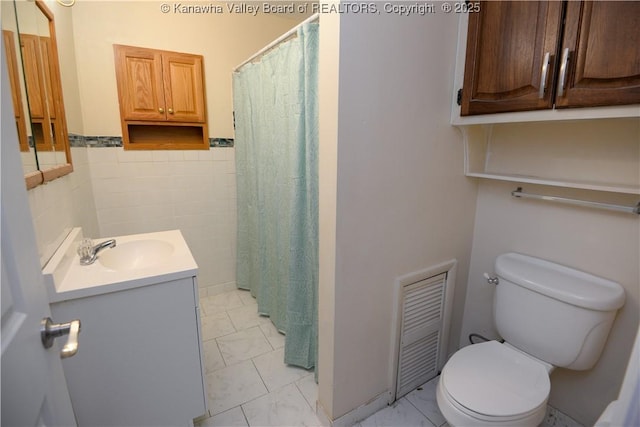 bathroom featuring vanity, toilet, and tile walls