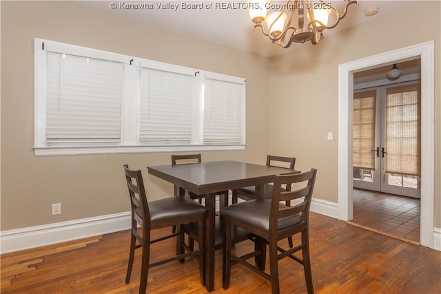 dining space featuring dark hardwood / wood-style floors, an inviting chandelier, and french doors