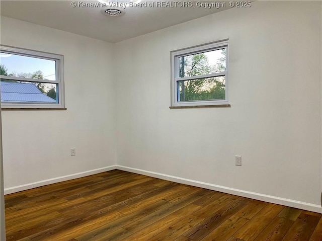 spare room featuring a healthy amount of sunlight and dark wood-type flooring