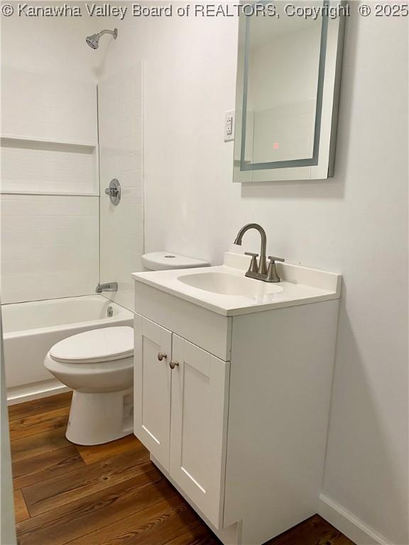 full bathroom with hardwood / wood-style flooring, shower / washtub combination, toilet, and vanity