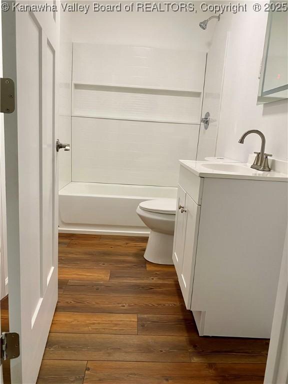 full bathroom with hardwood / wood-style flooring, vanity,  shower combination, and toilet