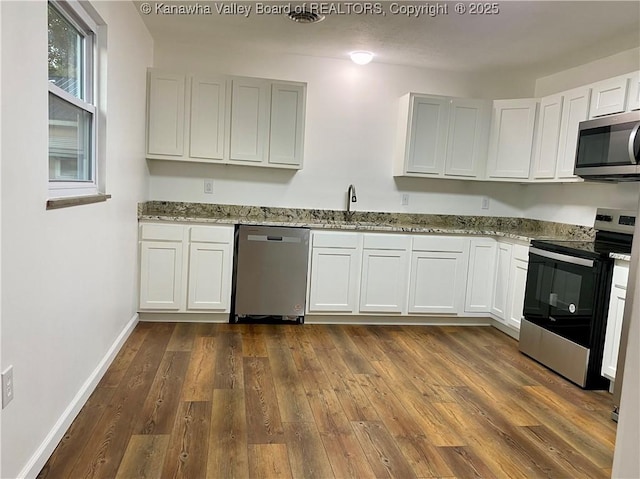 kitchen with stainless steel appliances, sink, white cabinets, and light stone counters