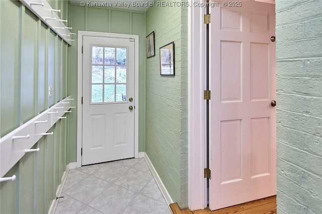 entryway with brick wall and light tile patterned floors