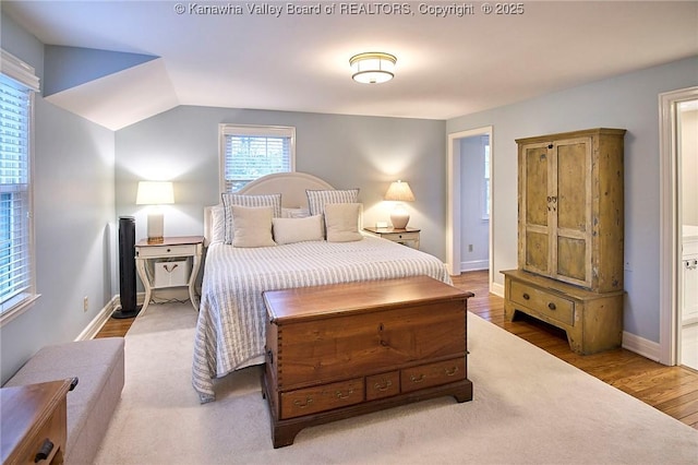 bedroom featuring vaulted ceiling, ensuite bathroom, and hardwood / wood-style floors