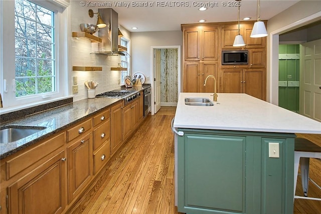 kitchen featuring appliances with stainless steel finishes, hanging light fixtures, an island with sink, a kitchen bar, and decorative backsplash