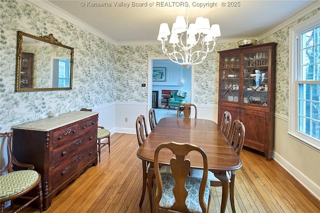 dining room featuring crown molding, a wealth of natural light, a chandelier, and light wood-type flooring