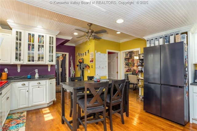 kitchen with white cabinetry, ornamental molding, stainless steel refrigerator, and light hardwood / wood-style floors