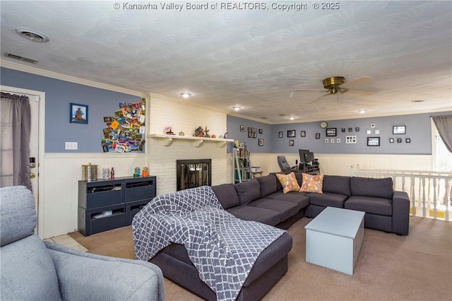 carpeted living room featuring crown molding, ceiling fan, a fireplace, and a textured ceiling