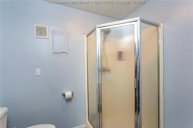 bathroom featuring toilet and a shower with shower door