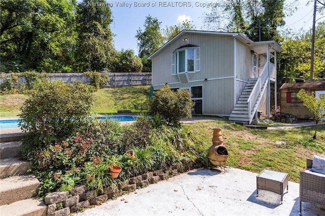 rear view of house with a fenced in pool and a patio