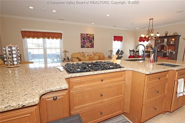 kitchen featuring black gas cooktop, light stone countertops, sink, and decorative light fixtures