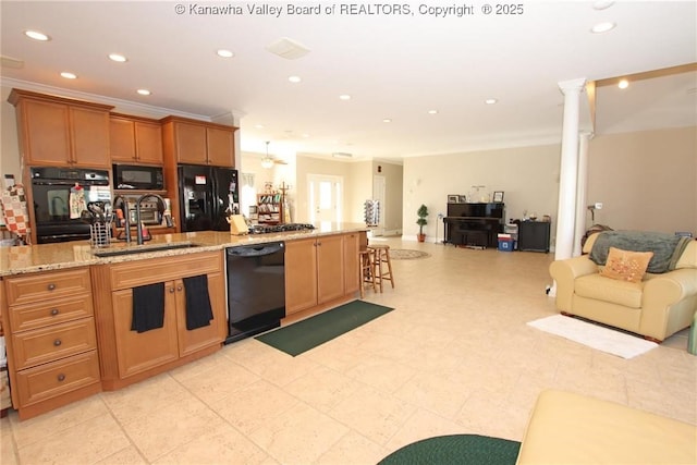 kitchen with sink, crown molding, decorative columns, light stone counters, and black appliances