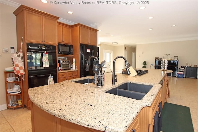 kitchen featuring sink, a kitchen island with sink, black appliances, crown molding, and light stone countertops