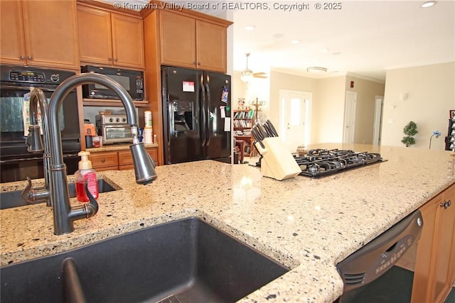 kitchen with light stone counters, sink, and black appliances