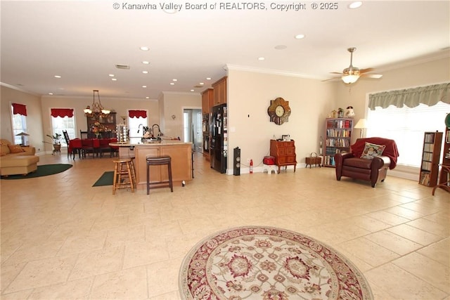 living room with ornamental molding, ceiling fan with notable chandelier, and a wealth of natural light