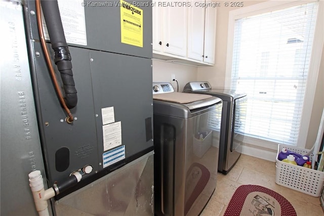 washroom featuring cabinets, washing machine and dryer, and light tile patterned flooring