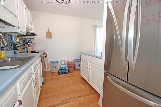 kitchen with white cabinetry, appliances with stainless steel finishes, backsplash, and light hardwood / wood-style flooring