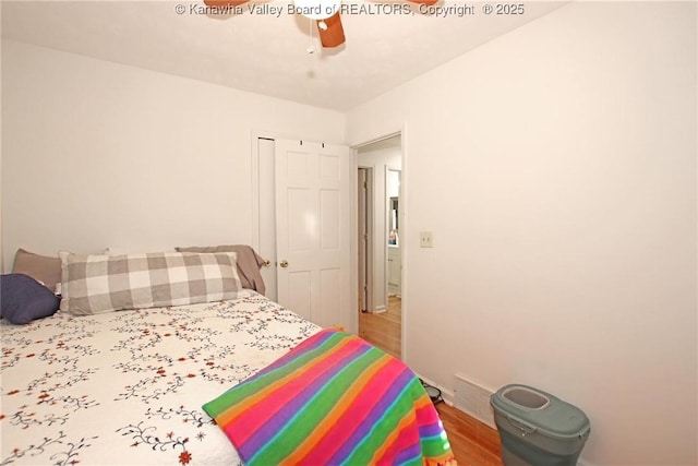 bedroom featuring hardwood / wood-style flooring, ceiling fan, and a closet