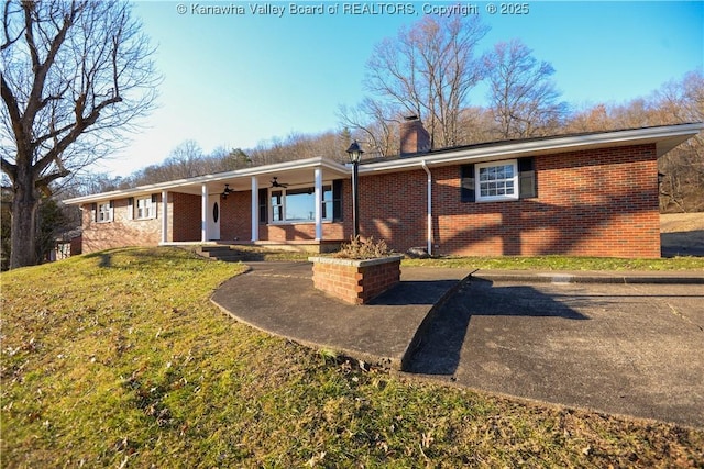 ranch-style home with ceiling fan, covered porch, and a front lawn