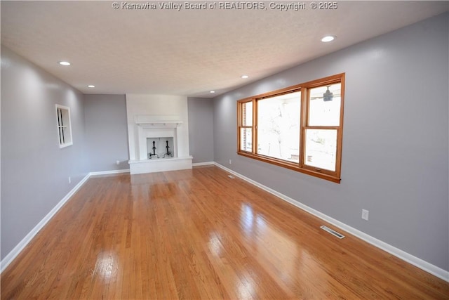 unfurnished living room with light hardwood / wood-style flooring and a textured ceiling