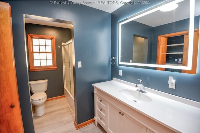 full bathroom with bath / shower combo with glass door, vanity, toilet, and hardwood / wood-style floors