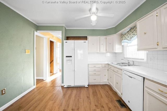 kitchen with white cabinetry, sink, light wood-type flooring, tile counters, and white appliances