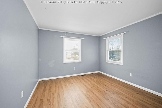 empty room with ornamental molding, plenty of natural light, and light hardwood / wood-style floors