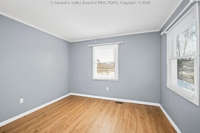 empty room featuring ornamental molding, a healthy amount of sunlight, and light wood-type flooring