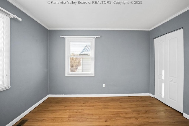 unfurnished bedroom featuring ornamental molding, wood-type flooring, and a closet