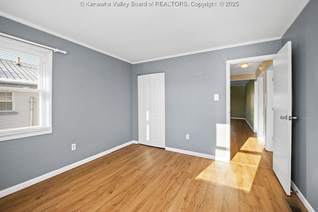 unfurnished bedroom with crown molding, light hardwood / wood-style floors, and a closet