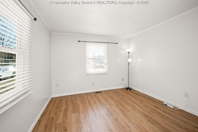 spare room featuring crown molding, a textured ceiling, and light wood-type flooring