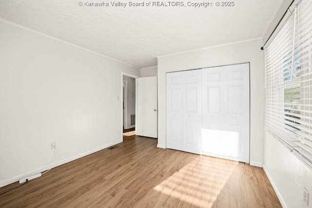 unfurnished bedroom featuring hardwood / wood-style flooring, ornamental molding, and a closet