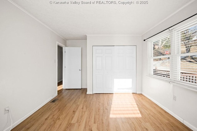 unfurnished bedroom featuring crown molding, a closet, and light wood-type flooring