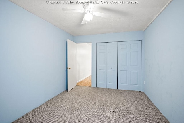 unfurnished bedroom with a textured ceiling, light colored carpet, a closet, and ceiling fan