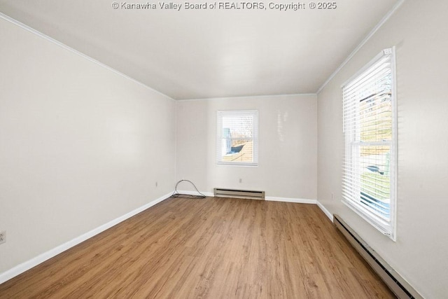 spare room with baseboard heating, a healthy amount of sunlight, and light hardwood / wood-style floors