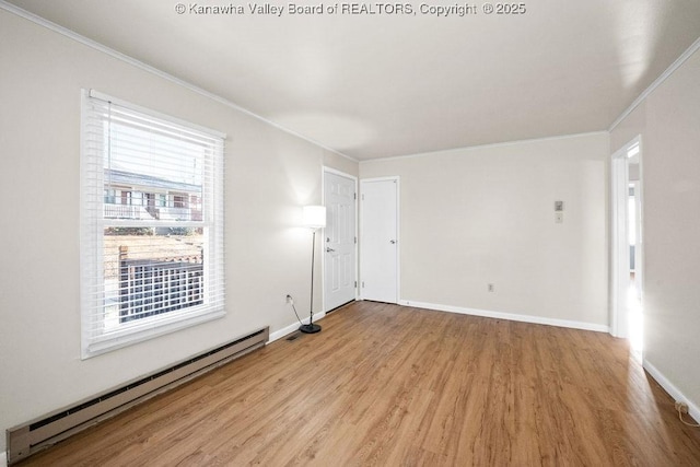 spare room featuring a baseboard heating unit, light hardwood / wood-style flooring, and ornamental molding