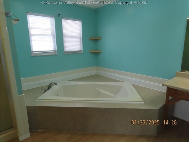 bathroom featuring vanity and tiled tub