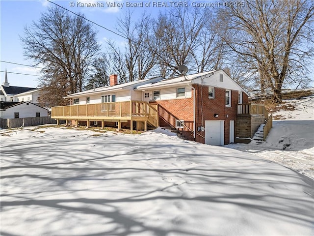 snow covered property featuring a garage and a wooden deck