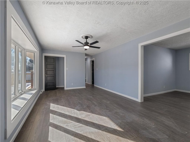 empty room with ceiling fan, dark hardwood / wood-style floors, and a textured ceiling