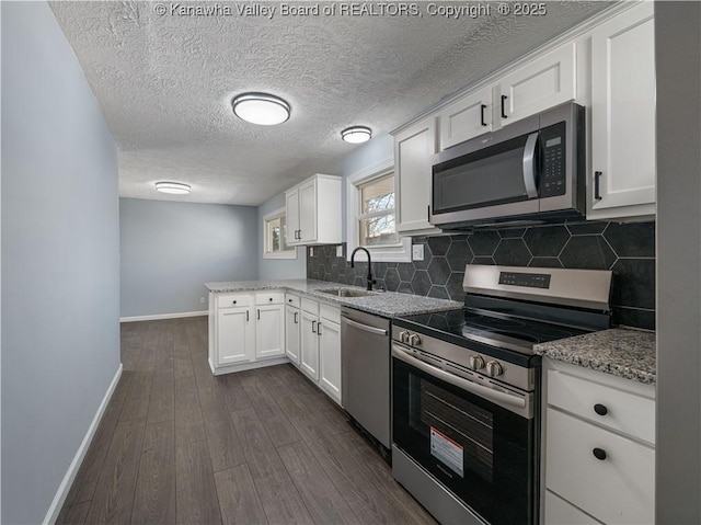 kitchen with dark hardwood / wood-style floors, sink, white cabinets, light stone counters, and stainless steel appliances