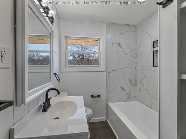 full bathroom featuring tiled shower / bath, hardwood / wood-style floors, vanity, toilet, and a textured ceiling