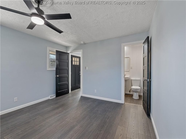 unfurnished bedroom with ceiling fan, dark hardwood / wood-style floors, connected bathroom, and a textured ceiling