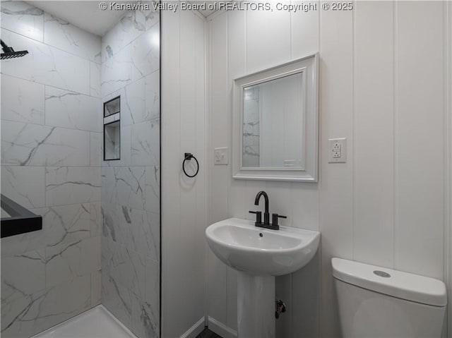 bathroom featuring tiled shower and toilet