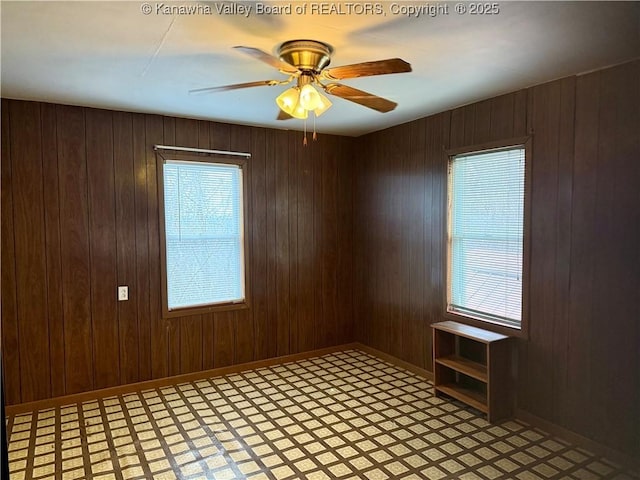 unfurnished room featuring wooden walls and ceiling fan