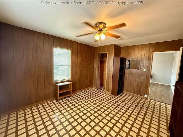 unfurnished room with ceiling fan and wood walls